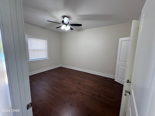 unfurnished room featuring dark wood-type flooring and ceiling fan