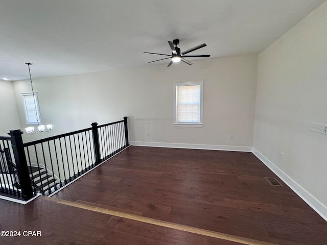 unfurnished room with dark hardwood / wood-style flooring and ceiling fan with notable chandelier