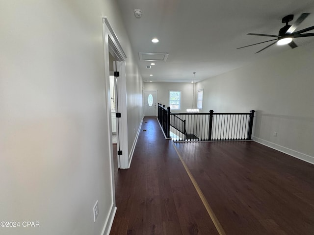 hallway with dark wood-type flooring and a notable chandelier