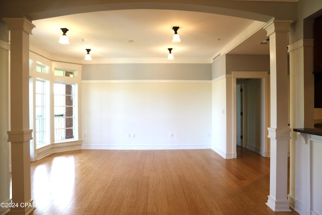 unfurnished room featuring light hardwood / wood-style flooring and ornate columns