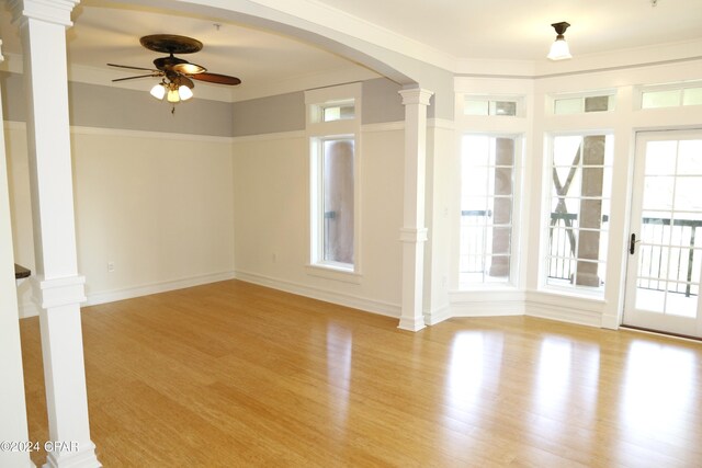 spare room with crown molding, ceiling fan, decorative columns, and light wood-type flooring