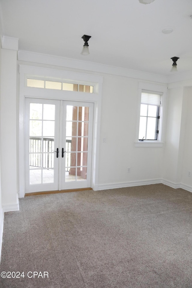 carpeted empty room with crown molding and french doors