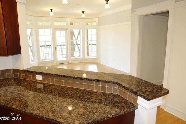 kitchen with dark stone countertops, light wood-type flooring, and kitchen peninsula