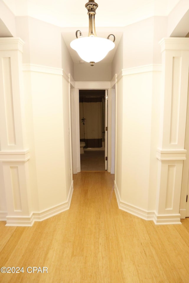 hallway featuring light hardwood / wood-style flooring and ornate columns