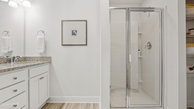 bathroom with a shower with shower door, wood-type flooring, and vanity