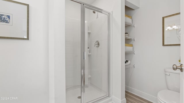 bathroom with hardwood / wood-style floors, an enclosed shower, and toilet