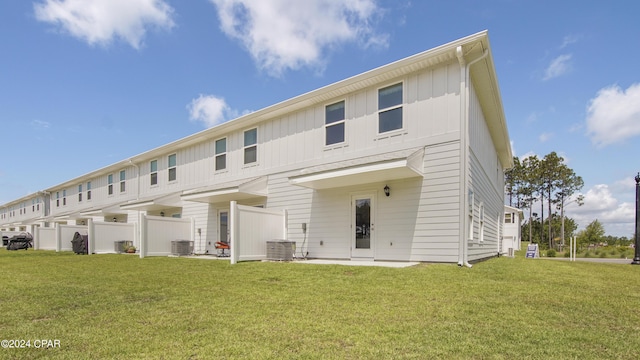 rear view of property with cooling unit and a yard