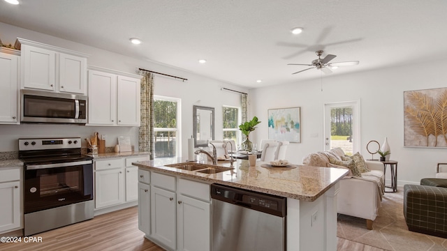 kitchen featuring sink, stainless steel appliances, light hardwood / wood-style flooring, a center island with sink, and white cabinets