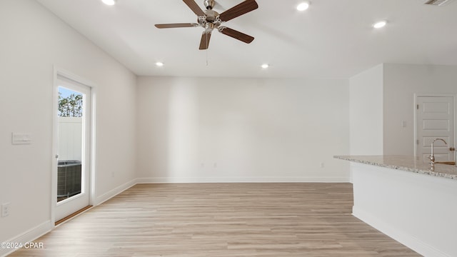 unfurnished living room featuring light wood-type flooring, sink, and ceiling fan