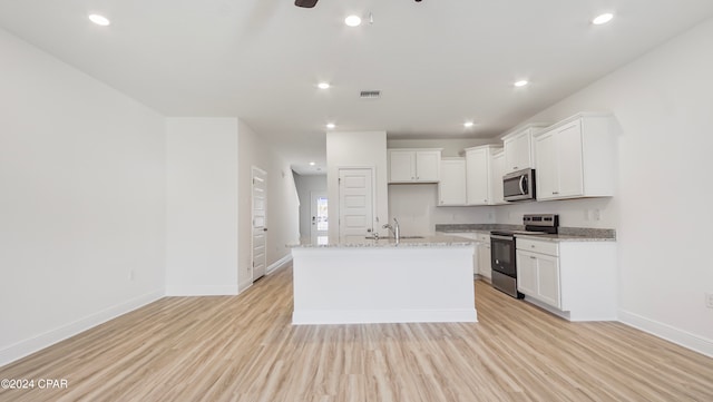 kitchen featuring light hardwood / wood-style floors, white cabinetry, a center island with sink, and appliances with stainless steel finishes