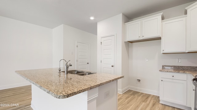 kitchen featuring white cabinets, a center island with sink, sink, and light hardwood / wood-style flooring