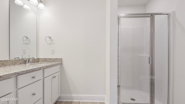 bathroom with hardwood / wood-style flooring, vanity, and an enclosed shower