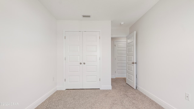 unfurnished bedroom featuring a closet and light colored carpet