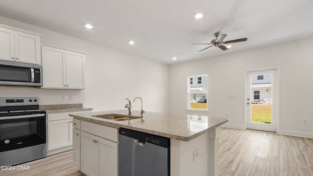 kitchen featuring stainless steel appliances, a center island with sink, white cabinets, sink, and light wood-type flooring