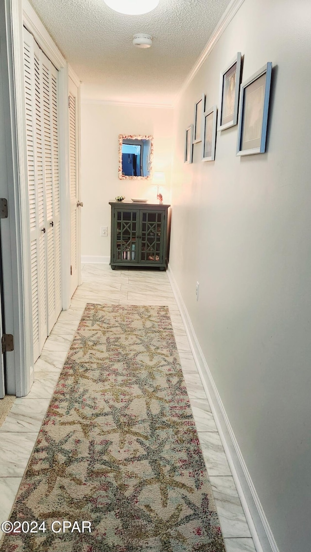 hallway with crown molding and a textured ceiling