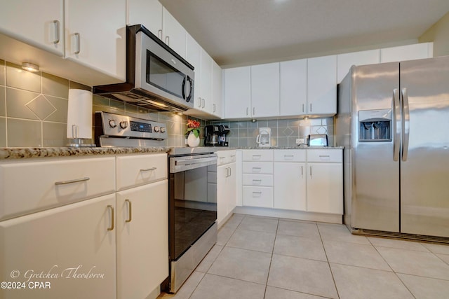 kitchen featuring white cabinets, appliances with stainless steel finishes, backsplash, and light tile patterned floors