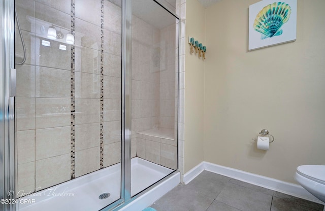 bathroom featuring toilet, tile patterned floors, and a shower with door