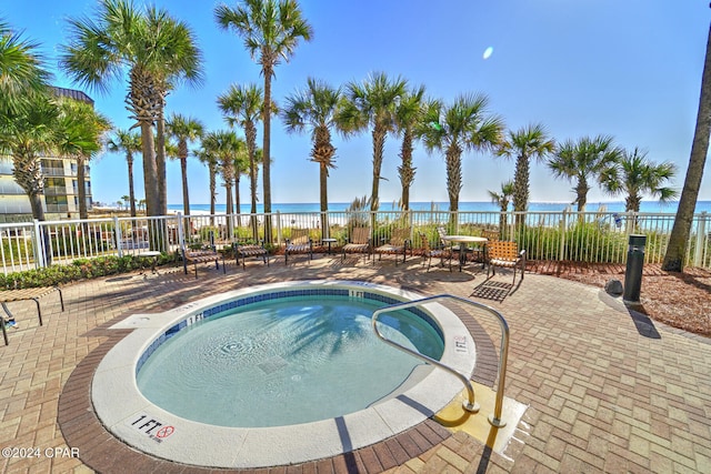 view of swimming pool with a community hot tub, a water view, and a patio