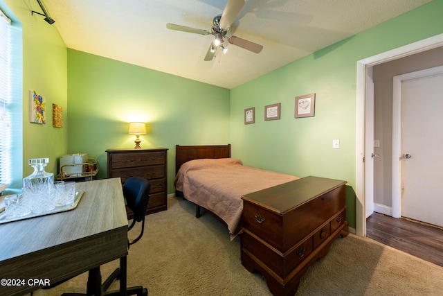 bedroom featuring ceiling fan, hardwood / wood-style floors, and a textured ceiling