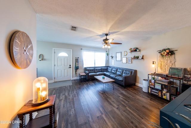 living room featuring ceiling fan, dark wood-type flooring, and a textured ceiling