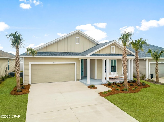 view of front facade with a porch, a garage, a front yard, and central AC unit