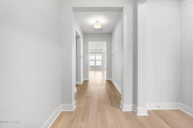 corridor with a raised ceiling and light wood-type flooring