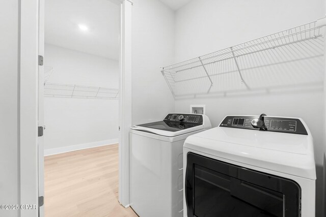 laundry area with separate washer and dryer and light hardwood / wood-style flooring