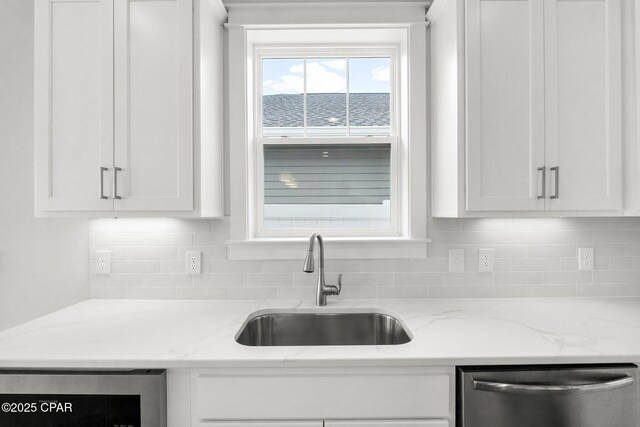 kitchen featuring white cabinetry, dishwasher, sink, decorative backsplash, and light stone countertops