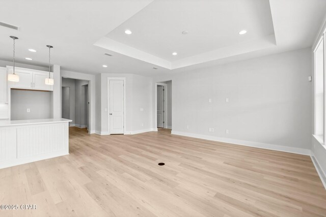 unfurnished living room with a tray ceiling and light hardwood / wood-style flooring