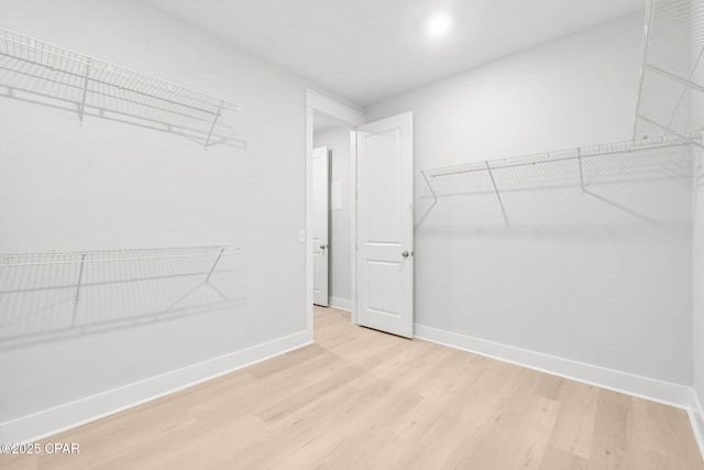 walk in closet with light hardwood / wood-style flooring