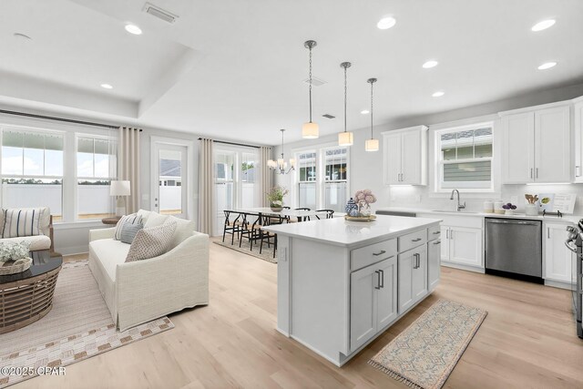 kitchen with white cabinetry, a center island, decorative light fixtures, and dishwasher