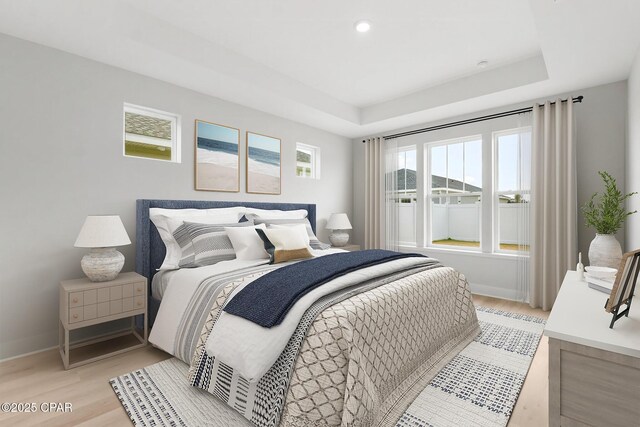 bedroom featuring a tray ceiling and light hardwood / wood-style floors