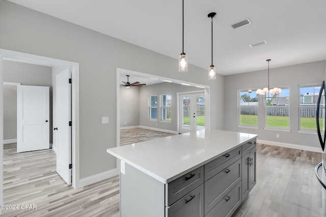 kitchen featuring a center island, ceiling fan with notable chandelier, light hardwood / wood-style floors, and decorative light fixtures