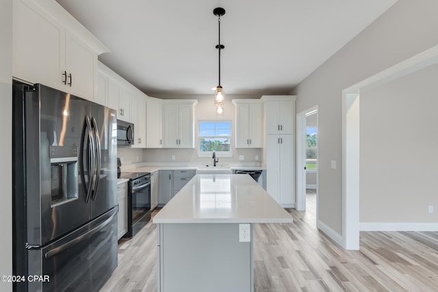 kitchen featuring a center island, light hardwood / wood-style floors, pendant lighting, white cabinets, and appliances with stainless steel finishes