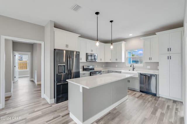 kitchen with a kitchen island, white cabinetry, hanging light fixtures, and appliances with stainless steel finishes