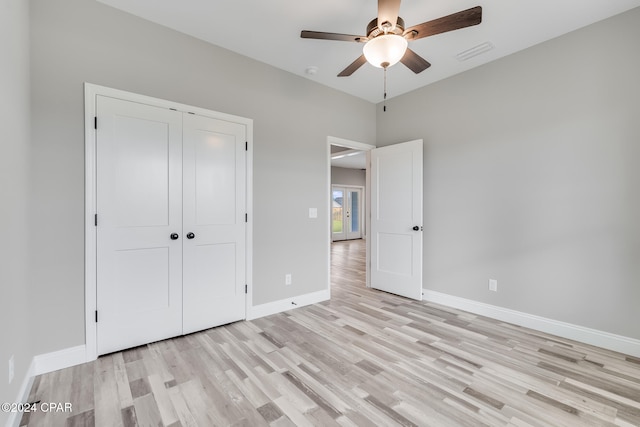 unfurnished bedroom with ceiling fan, light wood-type flooring, and a closet