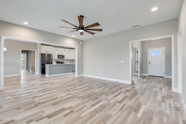 unfurnished living room featuring ceiling fan and light hardwood / wood-style floors