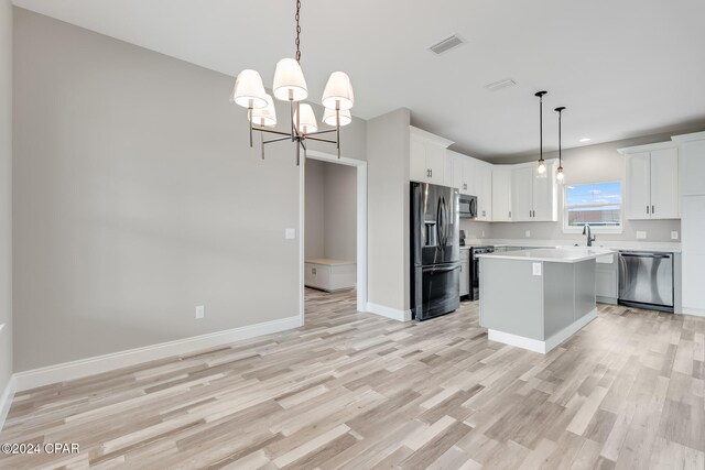 kitchen with appliances with stainless steel finishes, light wood-type flooring, decorative light fixtures, a center island, and white cabinetry