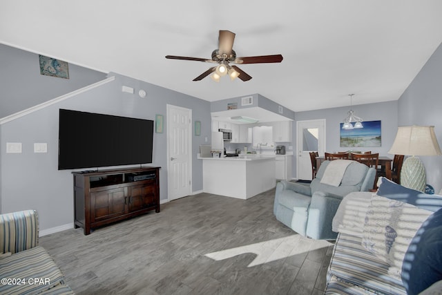 living room with ceiling fan with notable chandelier and light hardwood / wood-style flooring