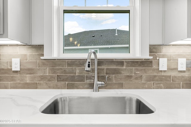 room details featuring white cabinetry, sink, and decorative backsplash