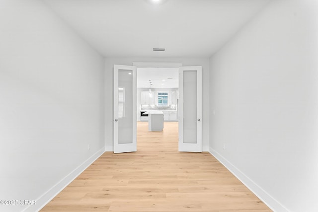 corridor featuring french doors and light hardwood / wood-style flooring