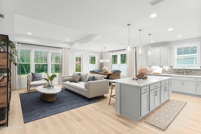 living room featuring sink, light hardwood / wood-style floors, and a healthy amount of sunlight