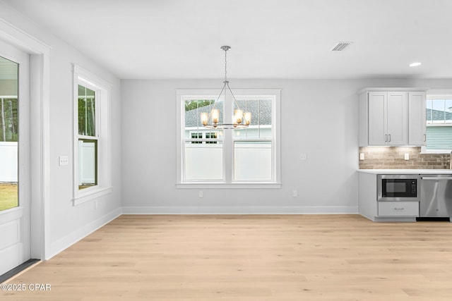 unfurnished dining area featuring an inviting chandelier and light wood-type flooring