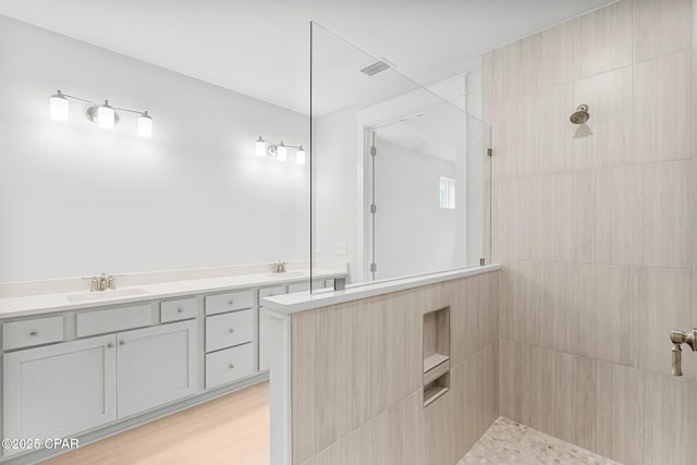 bathroom with vanity, wood-type flooring, and a tile shower