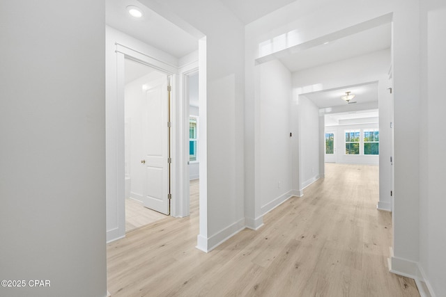 kitchen with stainless steel range, a raised ceiling, white cabinets, light hardwood / wood-style floors, and an island with sink