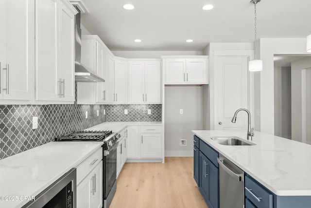 kitchen featuring appliances with stainless steel finishes, blue cabinets, white cabinetry, sink, and hanging light fixtures