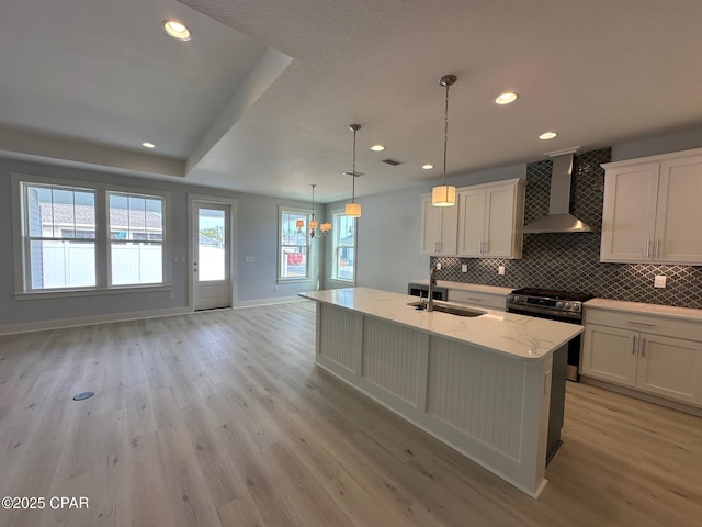 kitchen featuring white cabinets, sink, wall chimney exhaust hood, and decorative light fixtures