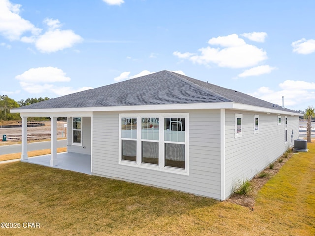 back of house with cooling unit, a patio area, and a lawn