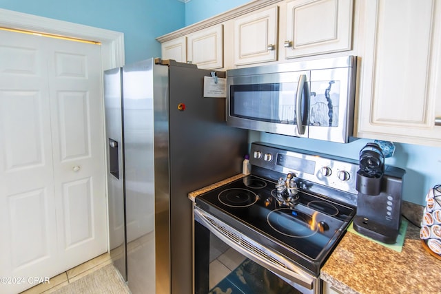 kitchen featuring light tile patterned floors, cream cabinetry, and appliances with stainless steel finishes