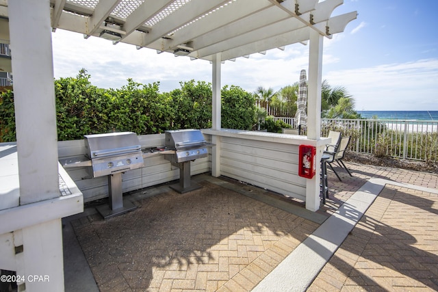 view of patio / terrace with a beach view, a pergola, a water view, and area for grilling